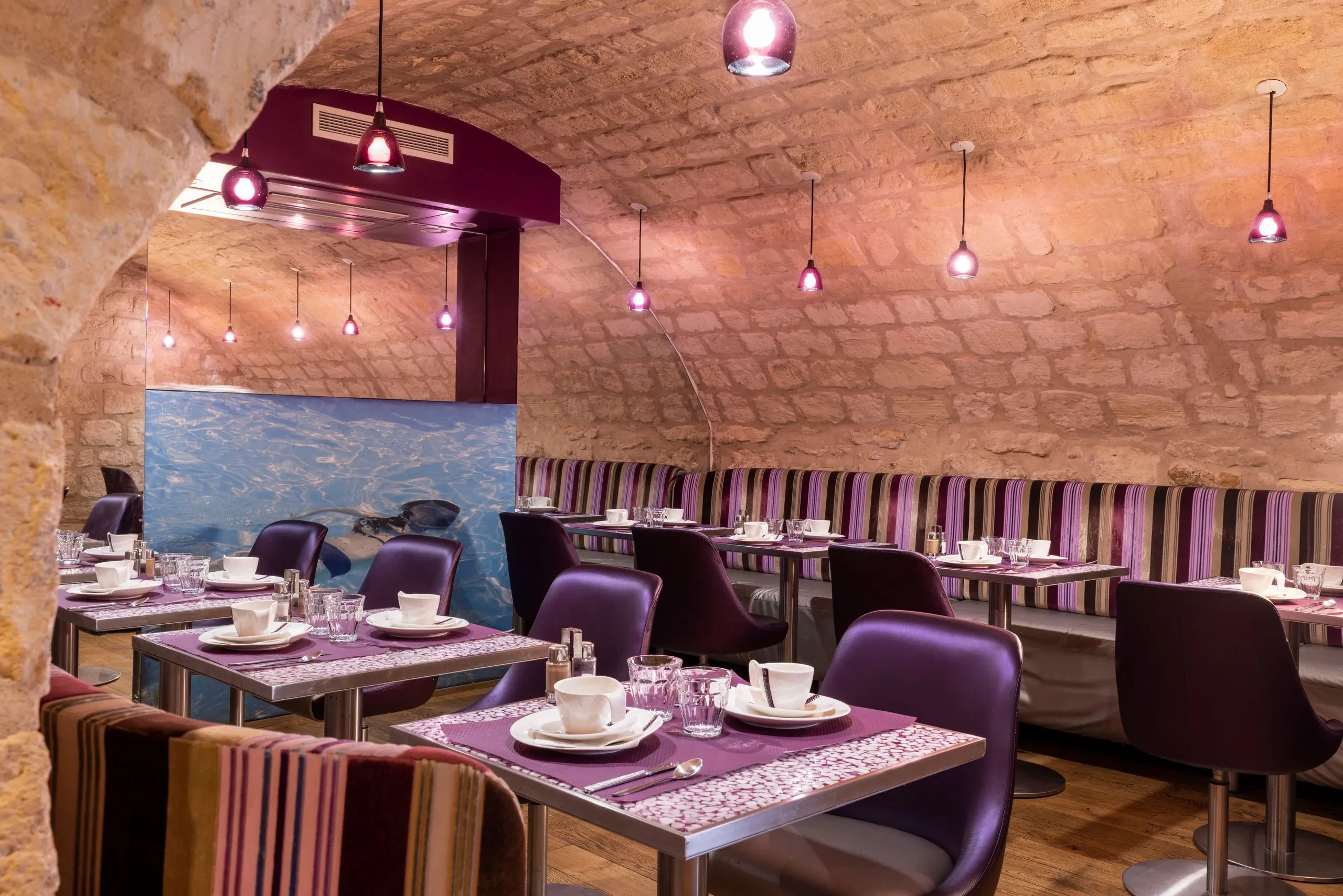 Salle de restaurant moderne avec alcôves en pierre.