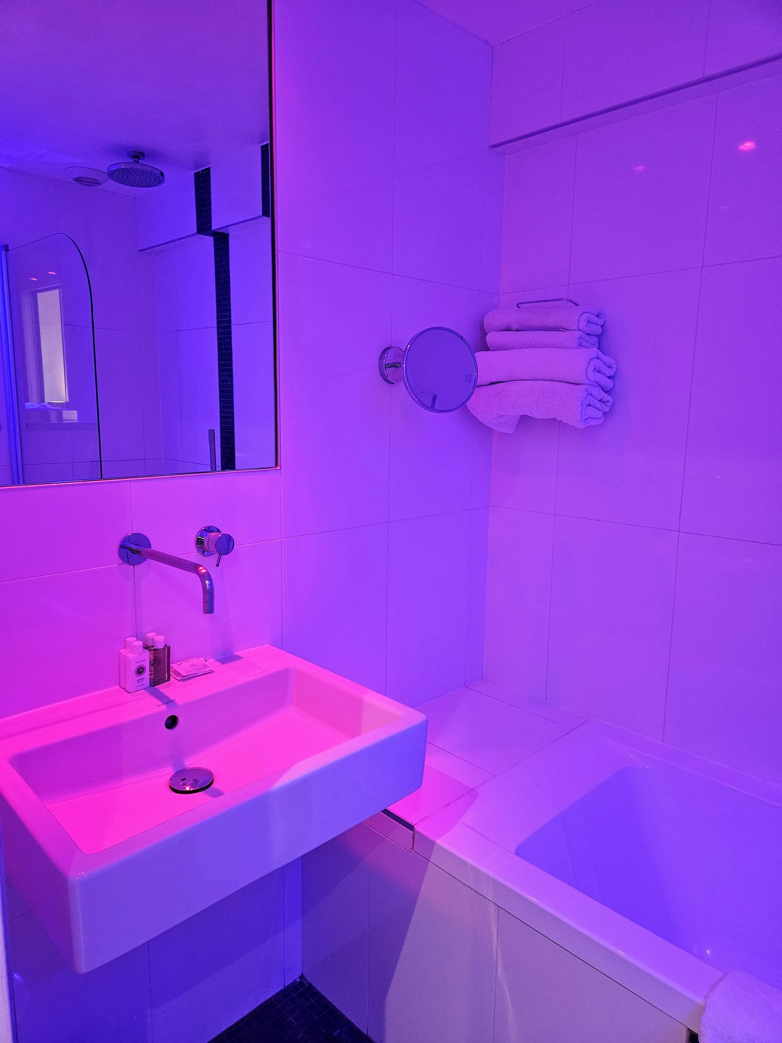 Salle de bain avec éclairage violet et lavabo moderne.