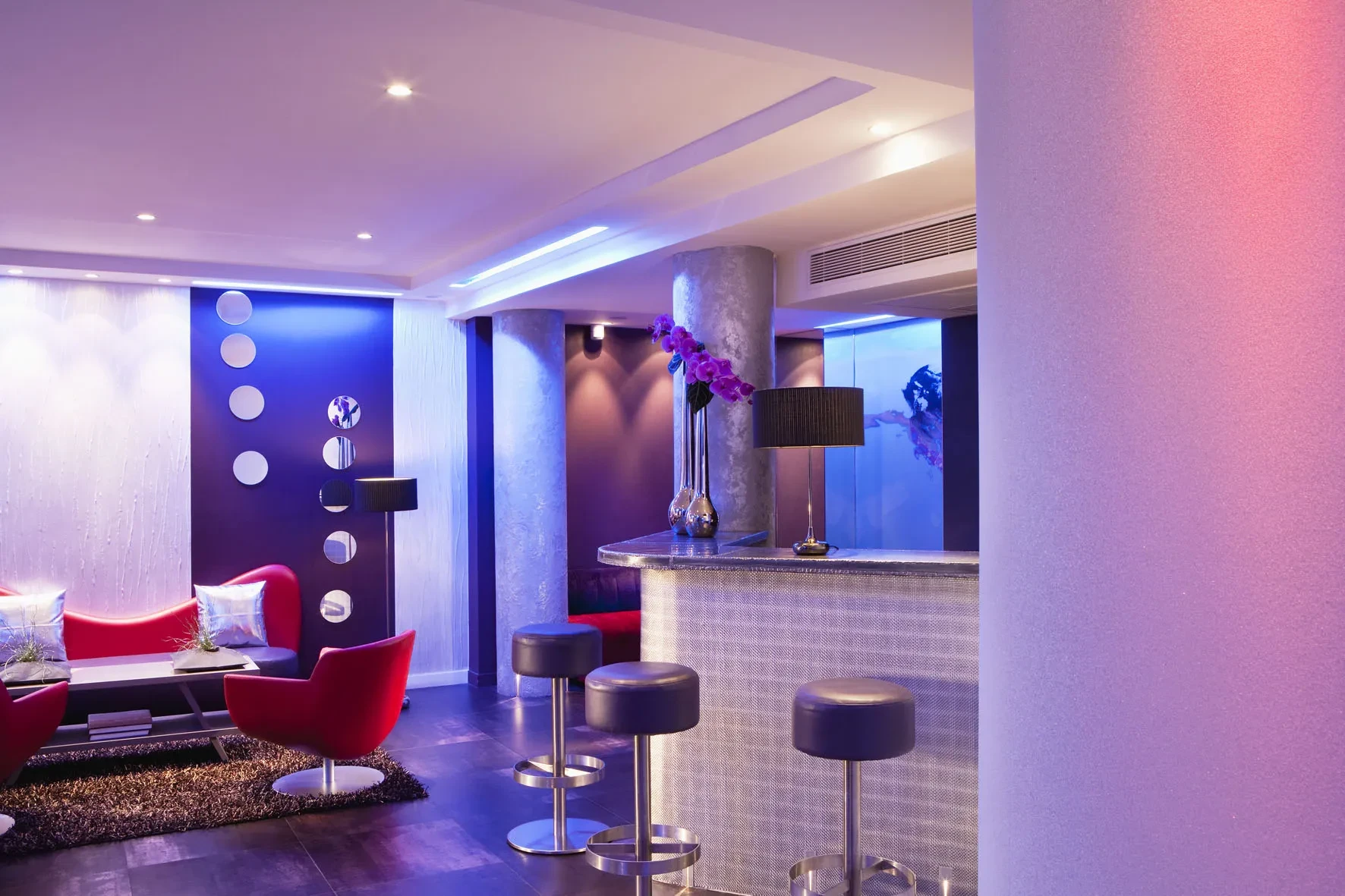 Salon moderne avec bar éclairé coloré.