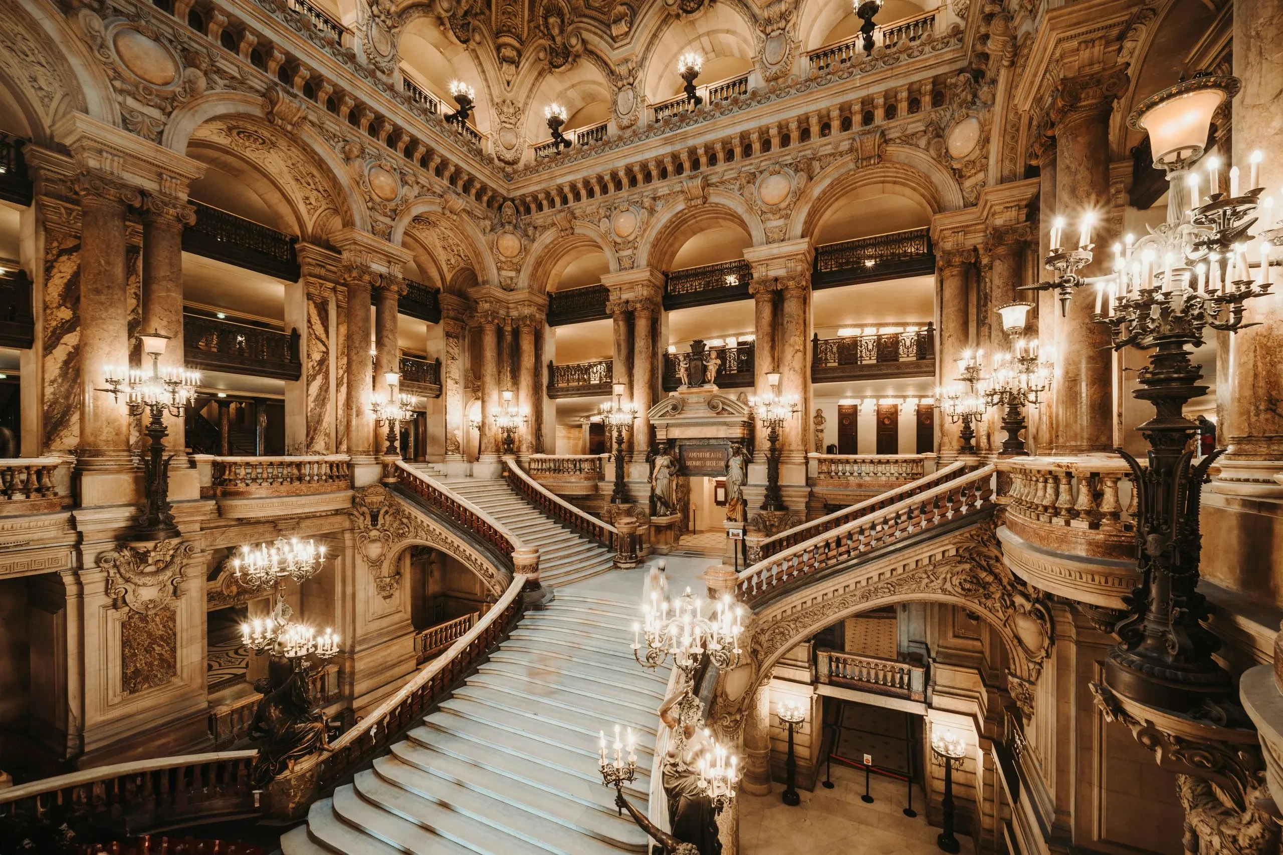 Intérieur somptueux d'un opéra avec escalier majestueux.